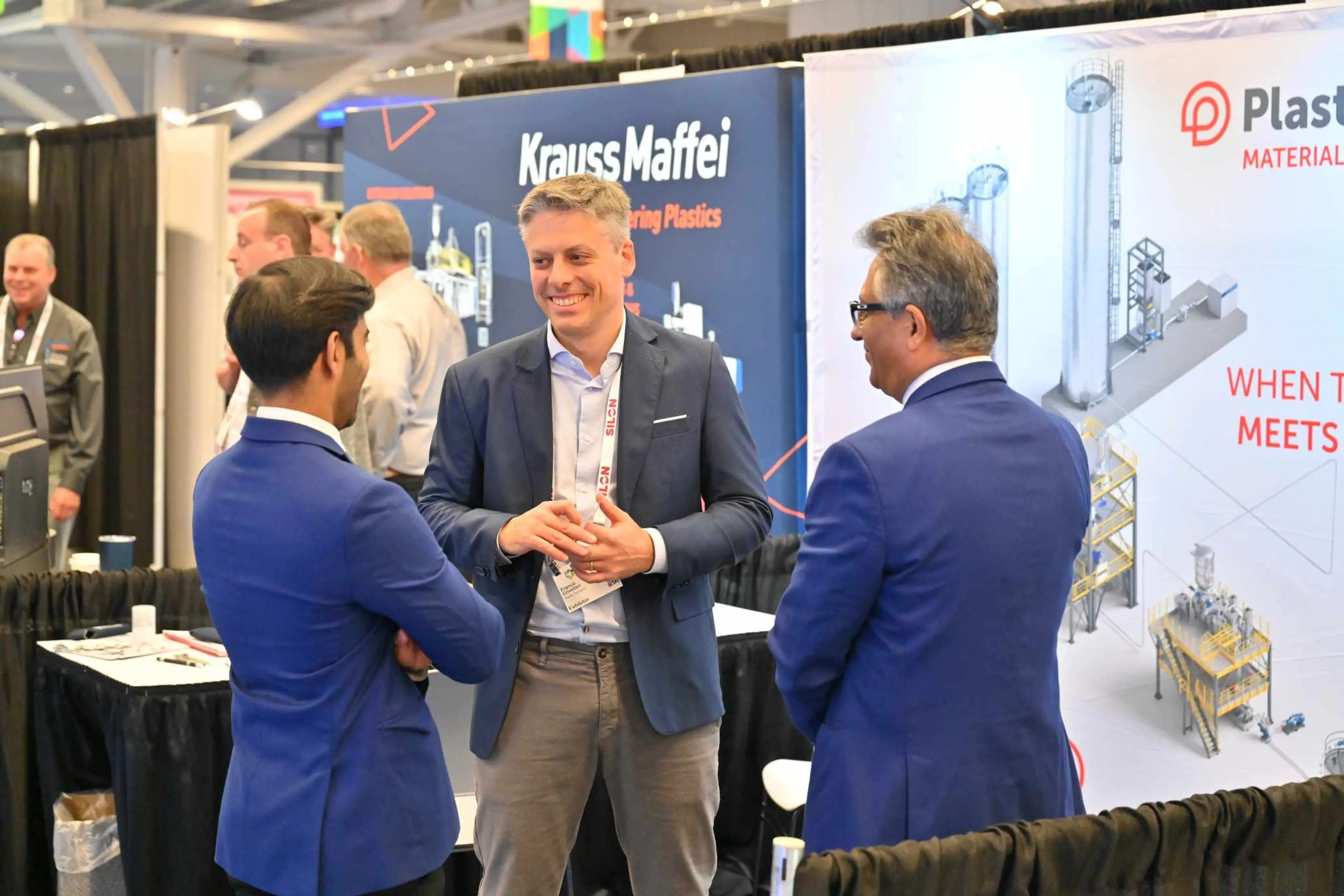 Conversations at AMI's Plastics World Expos - 3 men talking