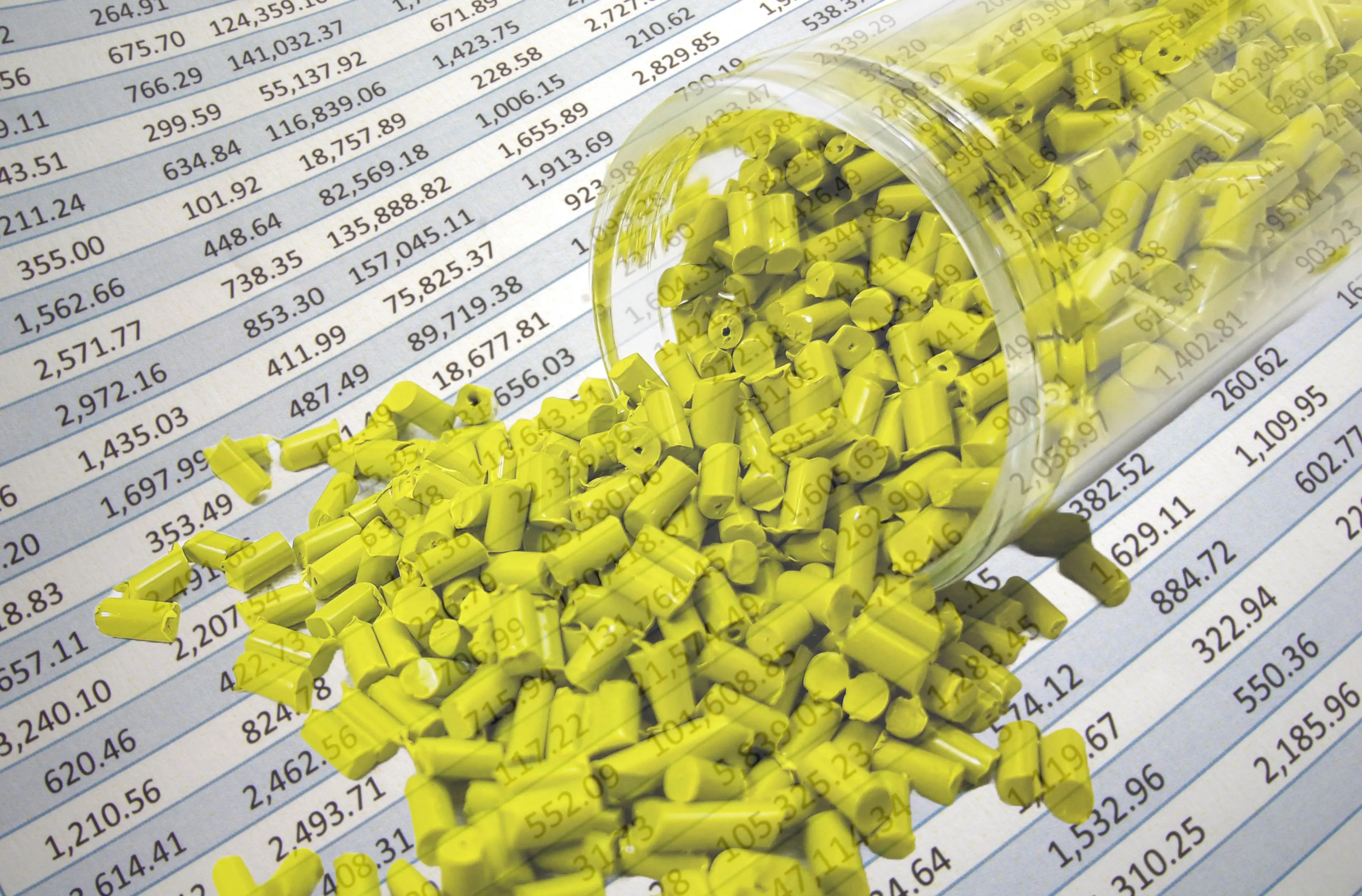 green plastic pellets in test tube with spreadsheet in background