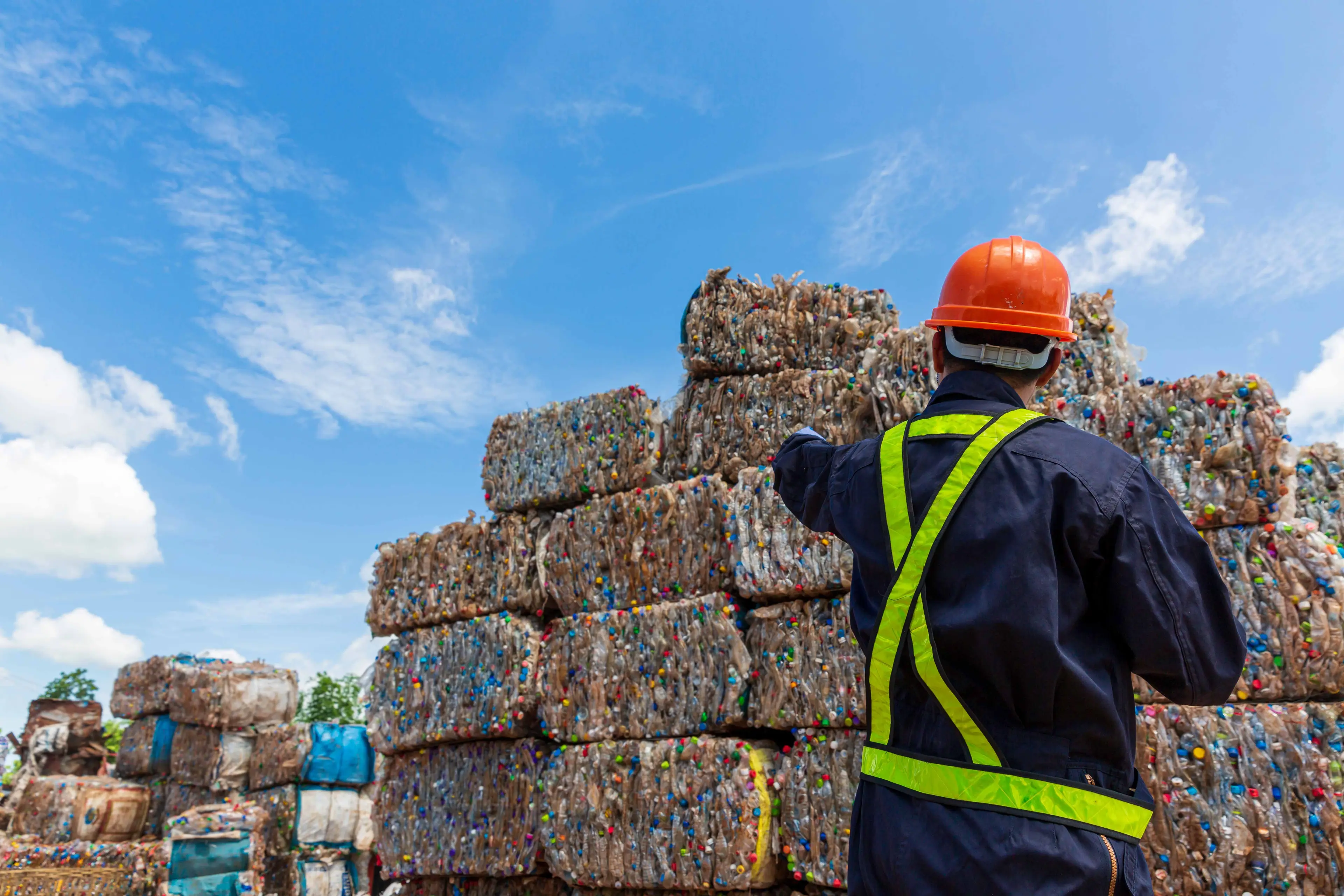 Recycling engineer looking at bales of recycled plastic bottles