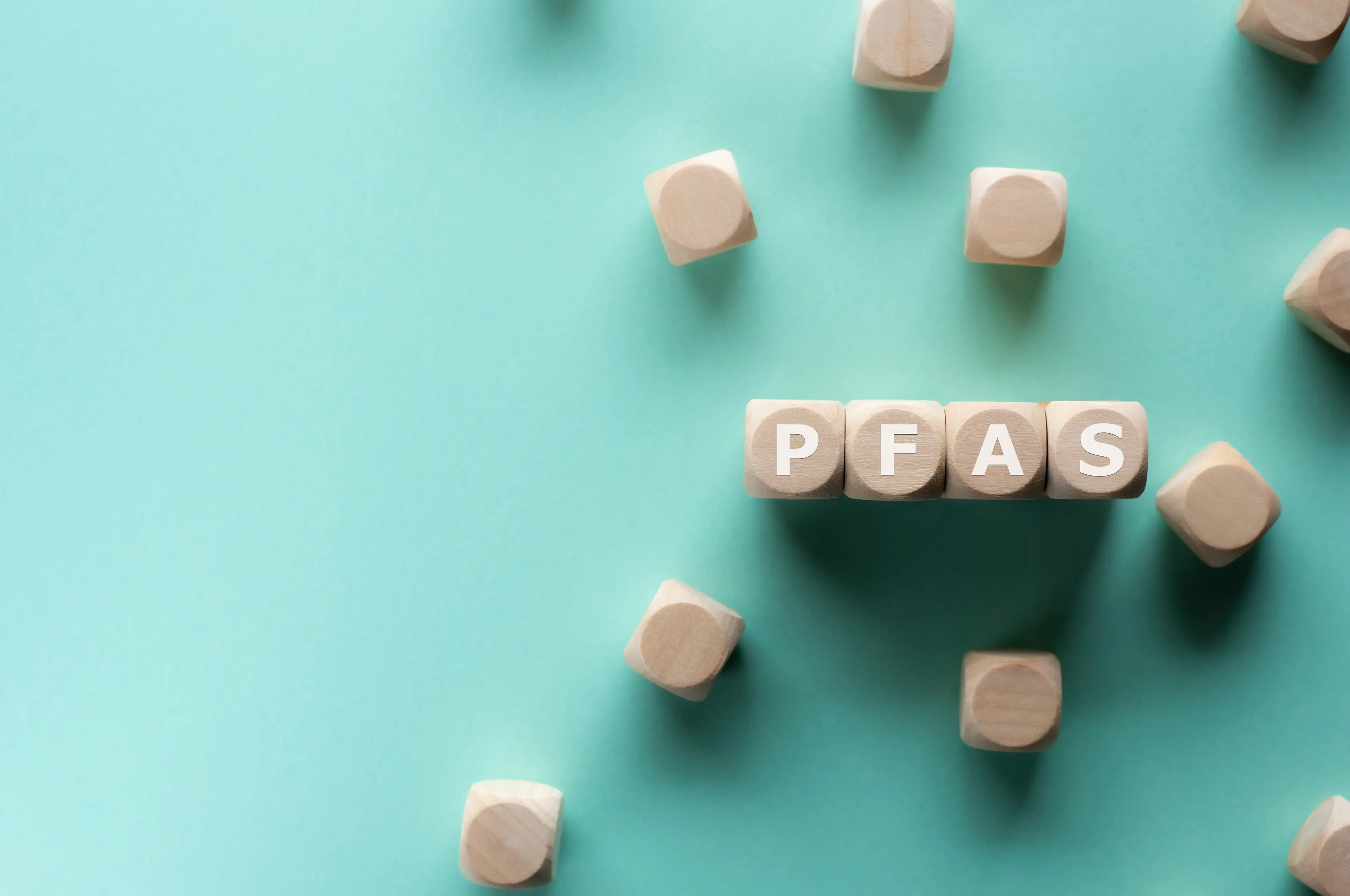 Wooden beads spelling PFAS on blue background